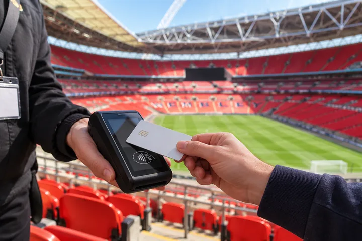 A contactless card payment with Wembley Stadium seats in the background